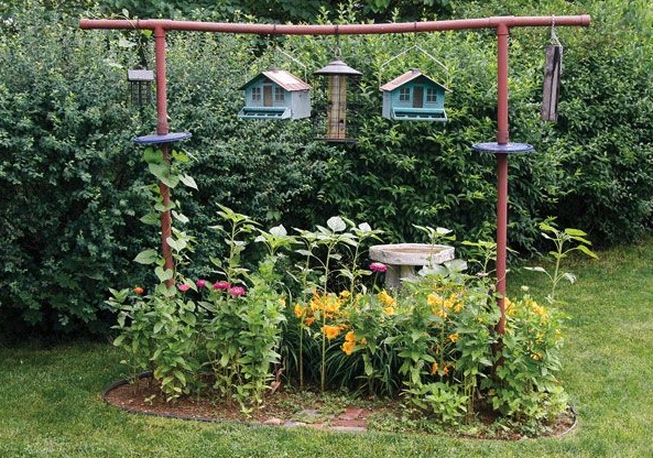A garden plot with bird feeders hanging over the garden bed.